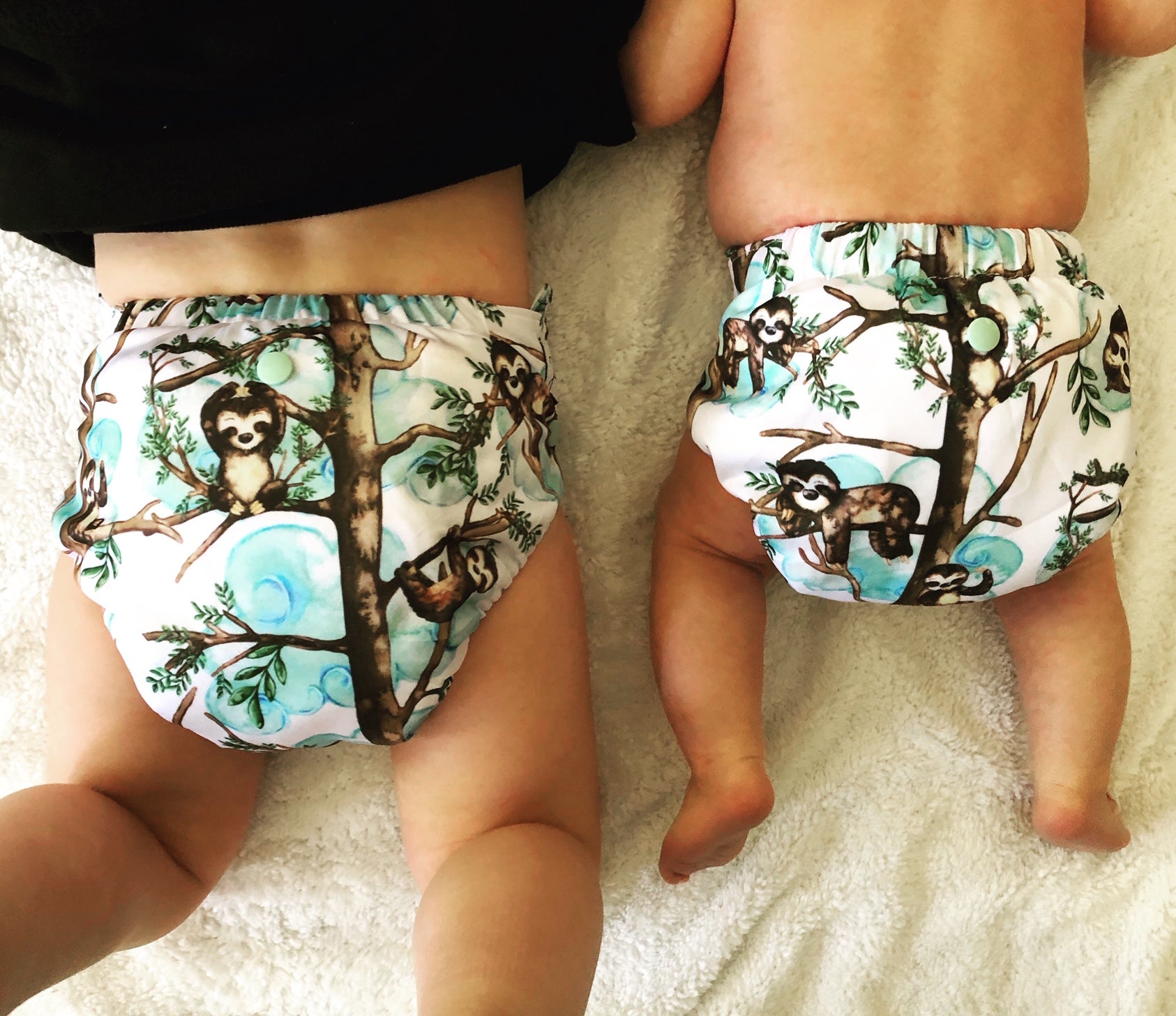 image of two children in cloth nappies one is around 2 years old and the other one month old. Both wearing matching sloth print cloth nappies